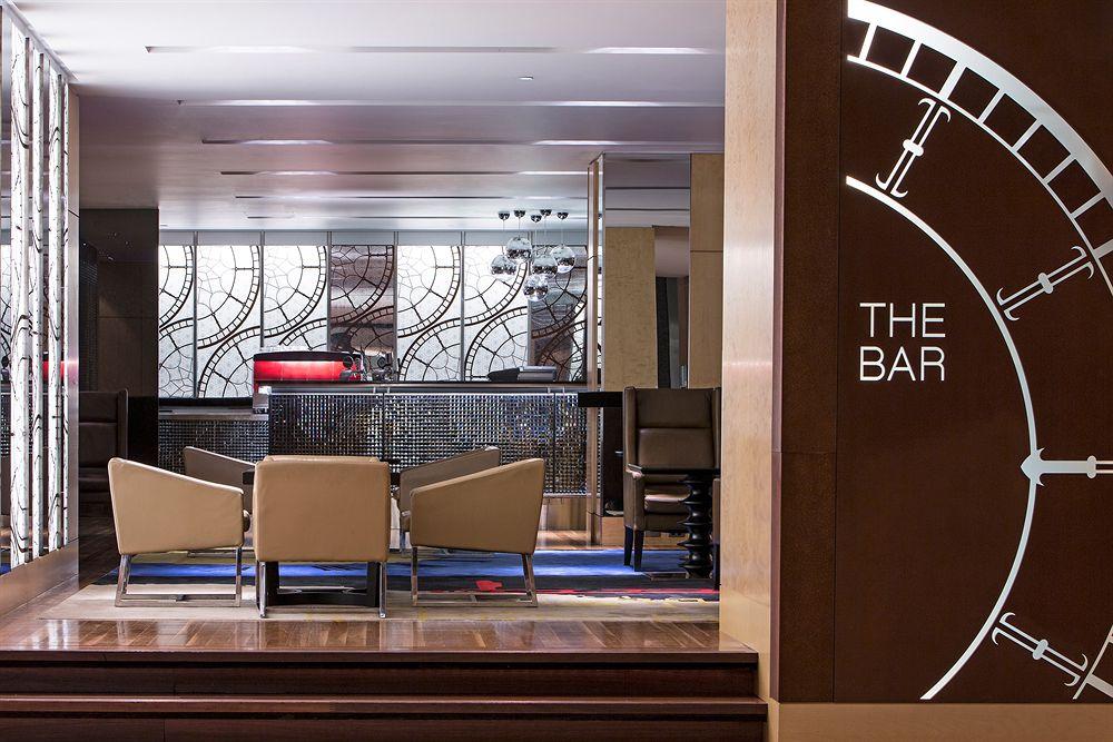 The Fullerton Hotel Sydney Esterno foto The photo shows a modern bar area. On the left side, there's a stylish sign that reads "THE BAR," integrated into a decorative design. In the center, behind a sleek counter, there appears to be a mirror with intricate patterns. The bar itself has a r