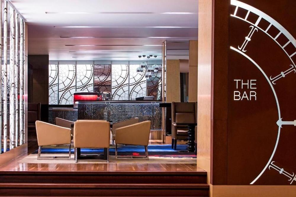 The Fullerton Hotel Sydney Esterno foto The photo shows a modern bar area with a stylish and elegant design. In the foreground, there are several upholstered chairs arranged around a small table. The bar counter is visible in the background, featuring a sleek design and various lighting el